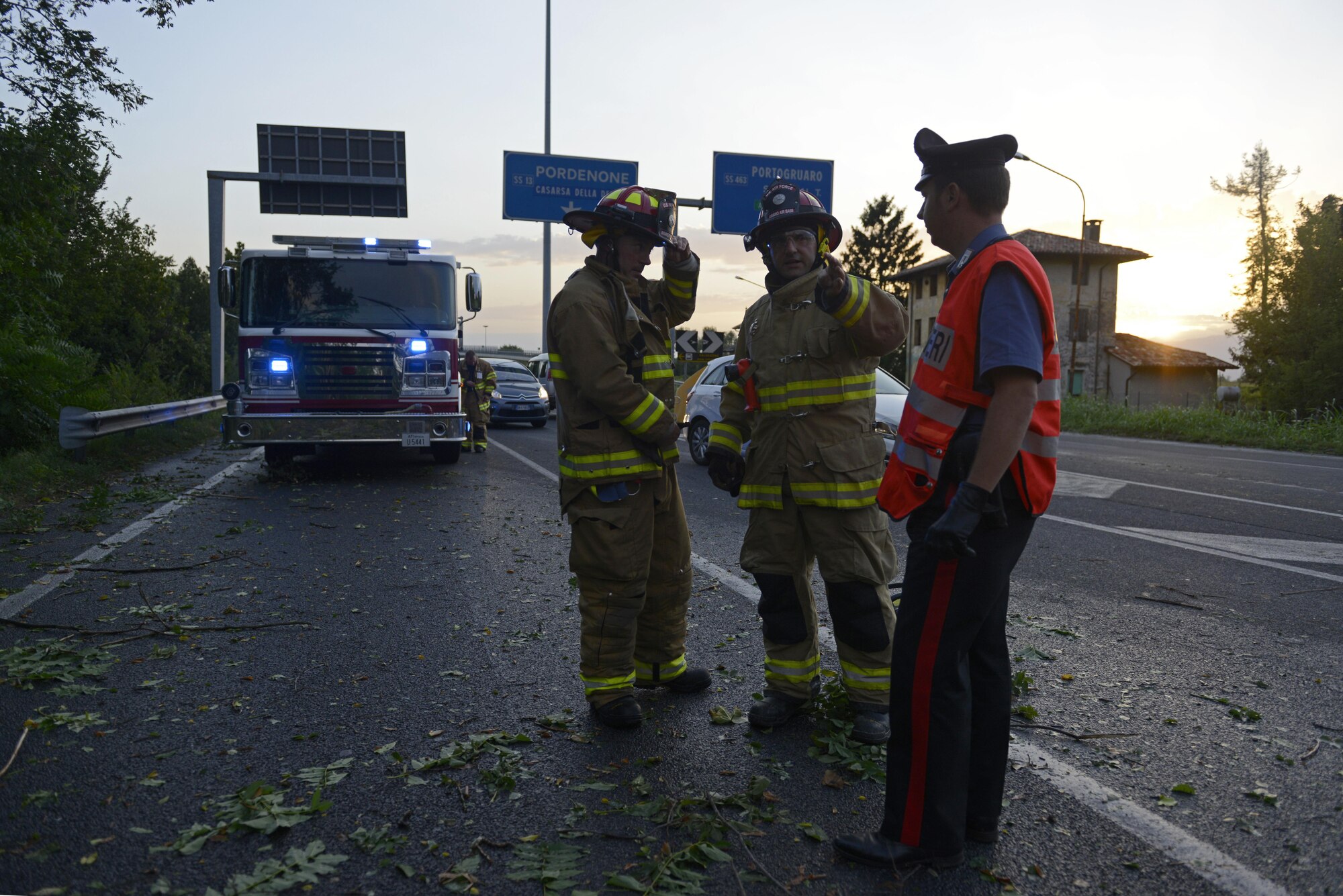 Aviano Air Base firefighters and a Carabinieri military police officer discuss removing a tree from a highway Aug. 10, 2017, in Pordenone Province, Italy. The 31st CES firefighters teamed with local first responders to clear roadways after heavy thunderstorms passed through the area. (U.S. Air Force photo by Tech. Sgt. Andrew Satran)