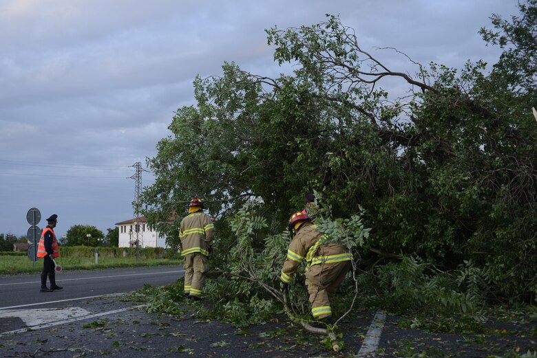 A Carabinieri military police officer and Aviano Air Base firefighters remove a tree from a highway Aug. 10, 2017, in Pordenone Province, Italy. The 31st CES firefighters teamed with local first responders to clear roadways after heavy thunderstorms passed through the area. (U.S. Air Force photo by Tech. Sgt. Andrew Satran)