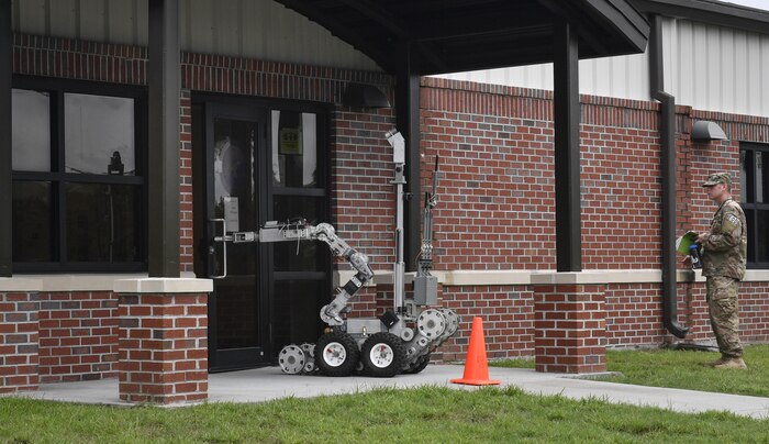 Tech. Sgt. Jonathan Morrison, 628th Civil Engineer Squadron explosive ordnance disposal technician, observes a robot inspecting the base mail center's entrance during an anti-terrorism exercise here, Aug. 9, 2017. The 628th EOD flight responded to a scenario and used the robot to search a simulated suspicious package during the exercise.