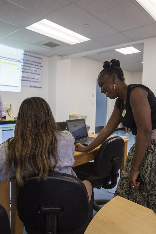 Alimat Adeniyi, branch manager, Shadow Mountain Branch Library, reviews previous work with Taylor Fourier, student, Maker Space Lab, at the Shadow Mountain Branch Library aboard the Marine Corps Air Ground Combat Center, Twentynine Palms, Calif., August 9, 2017. The library conducted the lab to foster excitement about the future of technology in children from military parents and open their minds to positive opportunities. (U.S. Marine Corps photo by Pfc. Margaret Gale)