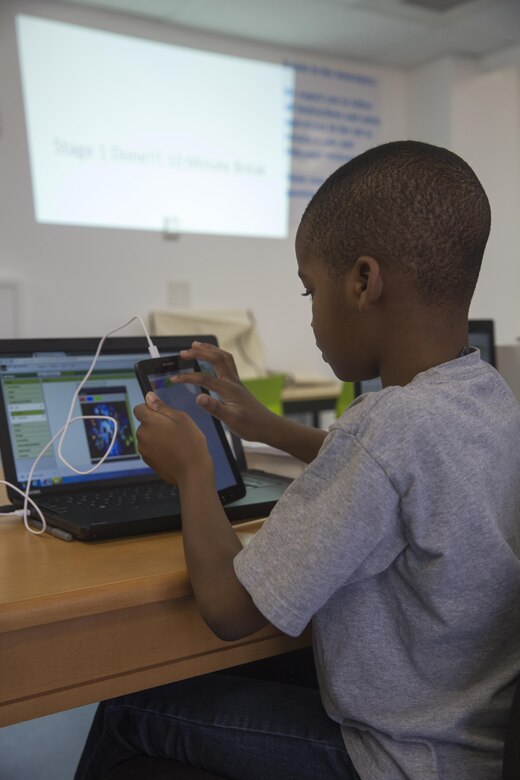 Michael Adeniyi, student, Maker Space Lab, transfers a photo to his mobile device at the Shadow Mountain Branch Library aboard the Marine Corps Air Ground Combat Center, Twentynine Palms, Calif., August 9, 2017. The library conducted the lab to foster excitement about the future of technology in children from military parents and open their minds to positive opportunities. (U.S. Marine Corps photo by Pfc. Margaret Gale)
