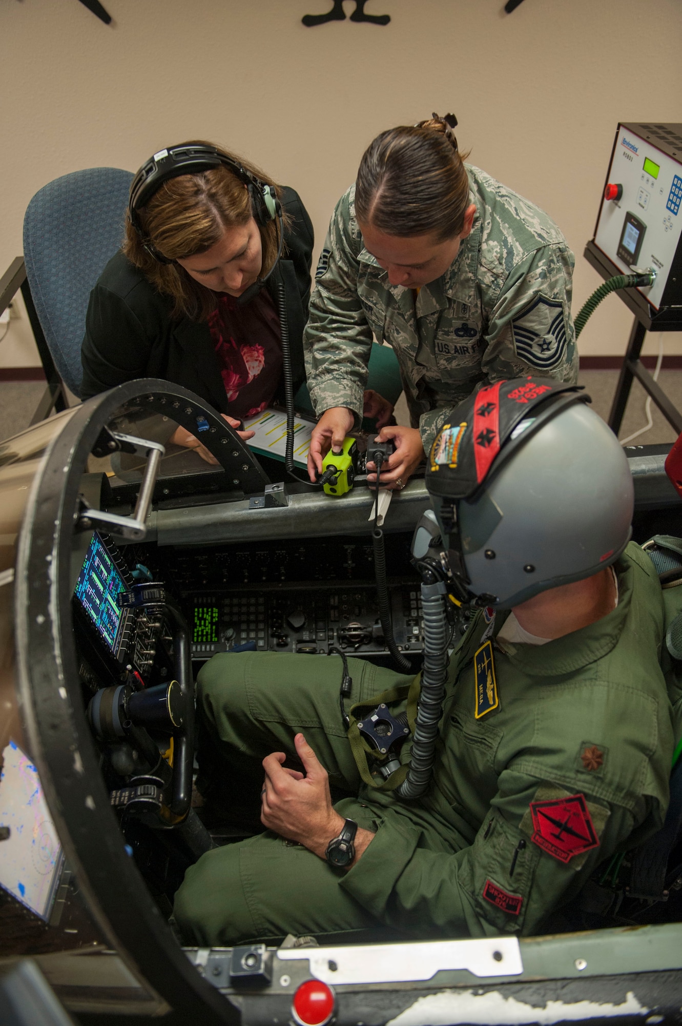 Master Sgt. Jennifer Flecker, 9th Physiological Support Squadron support flight chief, sets up the communication connection between the pilot and the rest of the support staff who will be monitoring the pilots vitals and the conditions of the simulation.