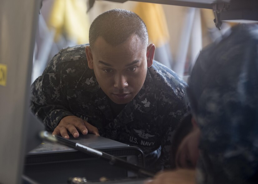 U.S. Navy Aviation Support Equipment Technician First Class Kunthea Sam, USS Abraham Lincoln (CVN-72), watches as Aviation Support Equipment Technician Second Class Eric Stark, 33rd Maintenance Squadron Aerospace Ground Equipment, discusses parts of an electric air conditioned cart during "Phase 1" initial training Aug. 9, 2017, at Eglin Air Force Base, Fla. The 33rd MXS's joint environment and extensive experience with both aircraft variants' support equipment makes the maintainers here most qualified to train and develop the Sailor's skills. (U.S. Air Force photo by Staff Sgt. Peter Thompson)