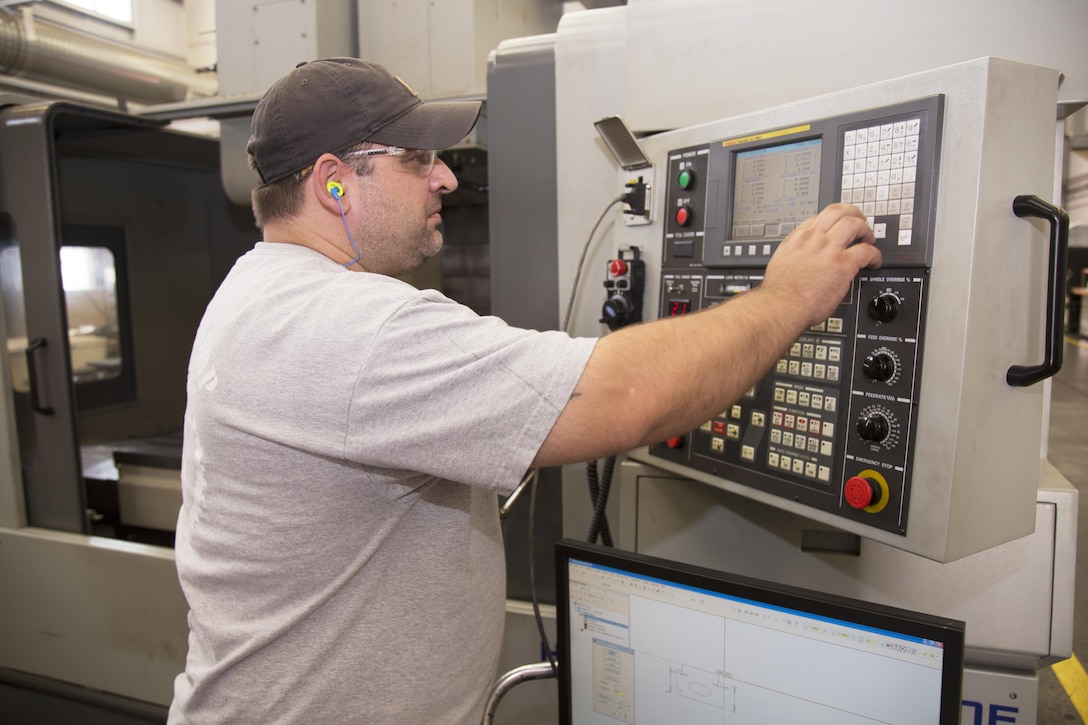 Machinist Tobin Anderson programs a Computer Numerical Controlled milling machine, at Production Plant Barstow, Calif., to make a tapping pad for a Light Armored Vehicle. Anderson said the CNC machine is capable of manufacturing parts that would be impossible or take too long to do by hand.