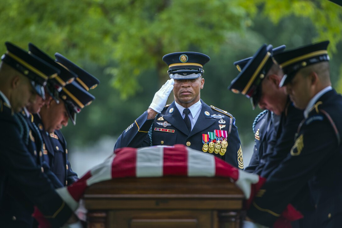 Soldiers render honors over a flag-draped casket.