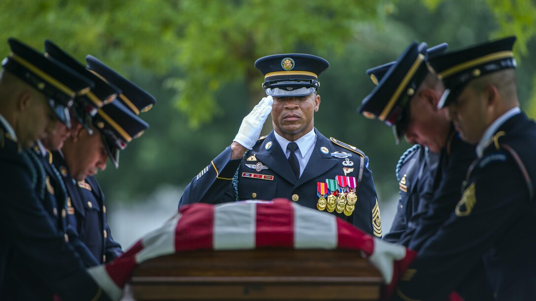 Soldiers render honors over a flag-draped casket.