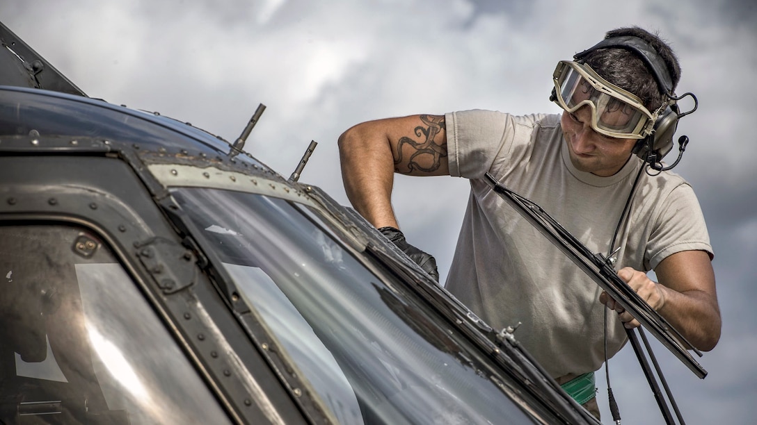 An airman washes a helicopter window.