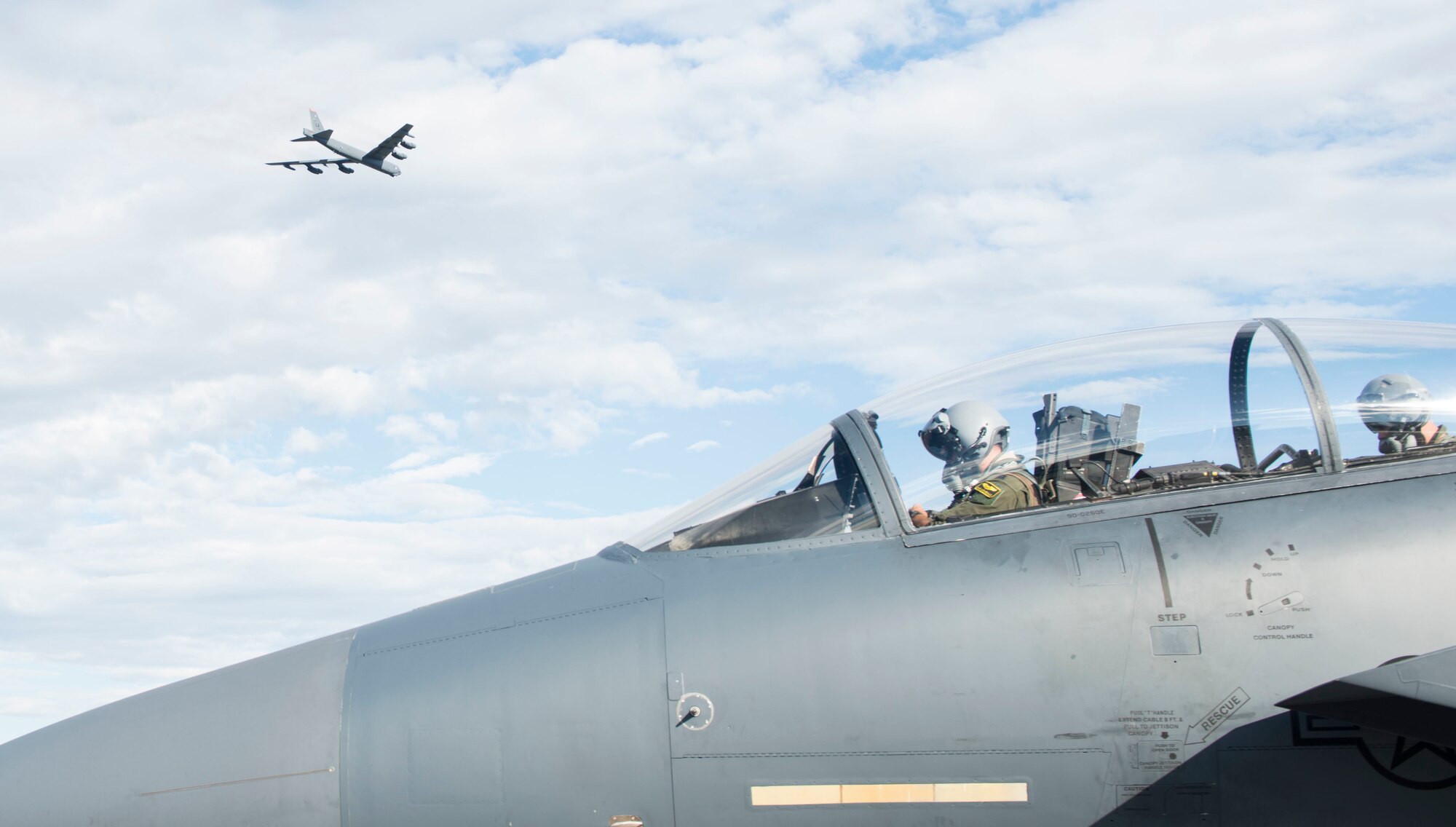 A B-52 Bomber flies over an F-15E Strike Eagle at Eielson Air Force Base, Idaho, August 8, 2017. Airmen from the 391st from Mountain Home Air Force Base, Idaho demonstrate their tactical prowess during Red Flag Alaska 17-3. (U.S. Air Force photo by Senior Airman Malissa Armstrong/Released)
