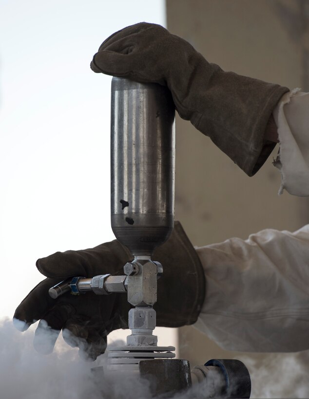 U.S. Air Force Senior Airman Samuel Fallot, a cryogenics journeyman with the 379th Expeditionary Logistics Readiness Squadron, Fuels Management Flight, removes a cryogenic sampler at Al Udeid Air Base, Qatar, Aug 9, 2017.