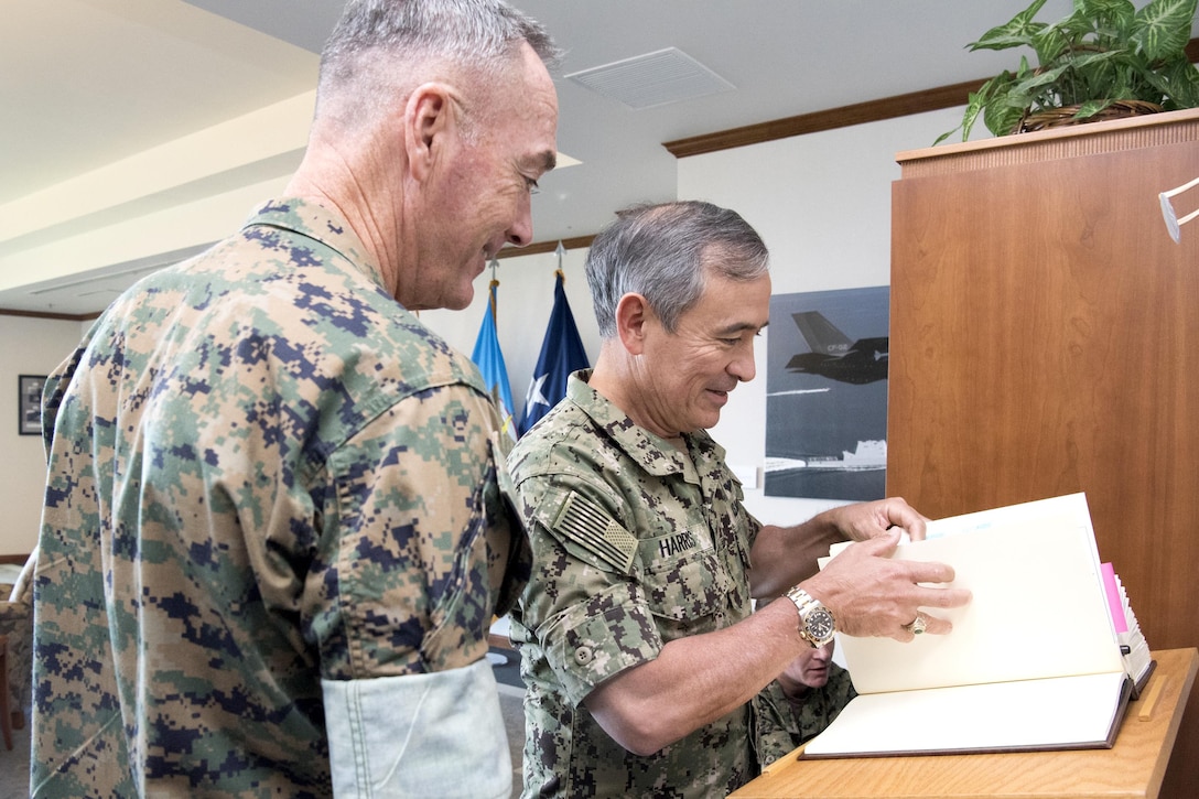 Marine Corps Gen. Joe Dunford and Pacom's commander look through pages of a book.