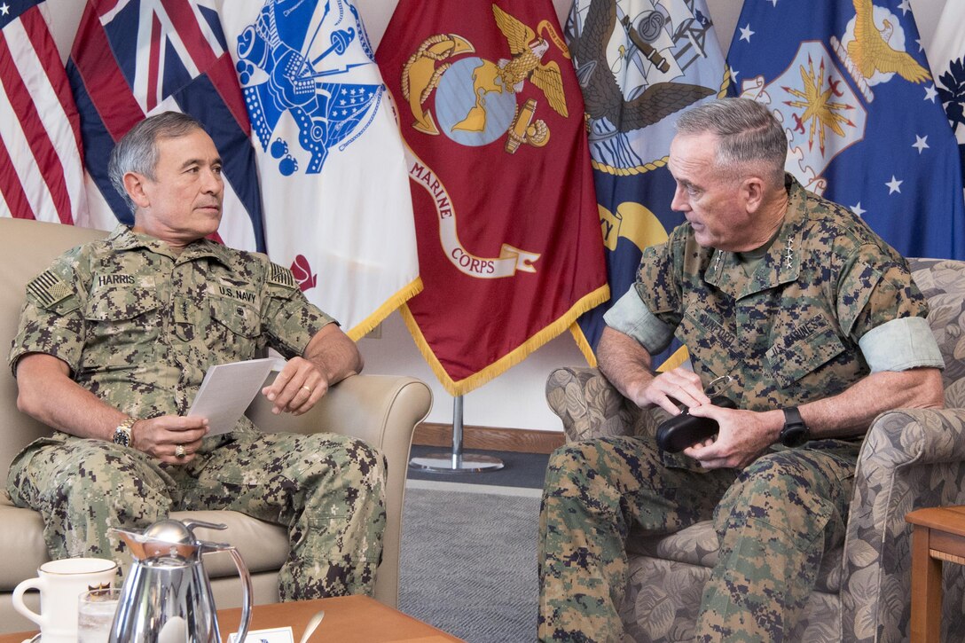 A Marine general and a Navy admiral sit and talk inside a room.