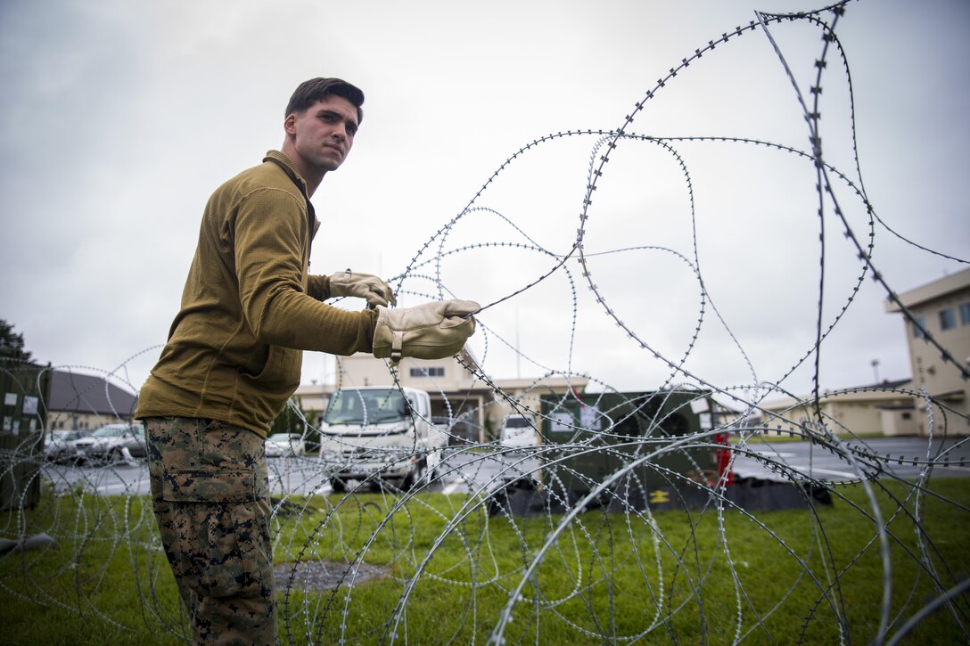 Pfc. James P. Gross, a radio and satellite communications operator, places barbed wire on the ground at Misawa Air Base, Japan, August 10, 2017, signifying the start of exercise Northern Viper 2017. This exercise tests the interoperability and bilateral capability of the Japan Ground Self-Defense Force and U.S. Marine Corps forces to work together and provides the opportunity to conduct realistic training in an unfamiliar environment. Gross, a Milwaukee native, is with Marine Wing Communications Squadron 18, Marine Air Control Group 18, 1st Marine Aircraft Wing. (U.S. Marine Corps photo by Lance Cpl. Andy Martinez)