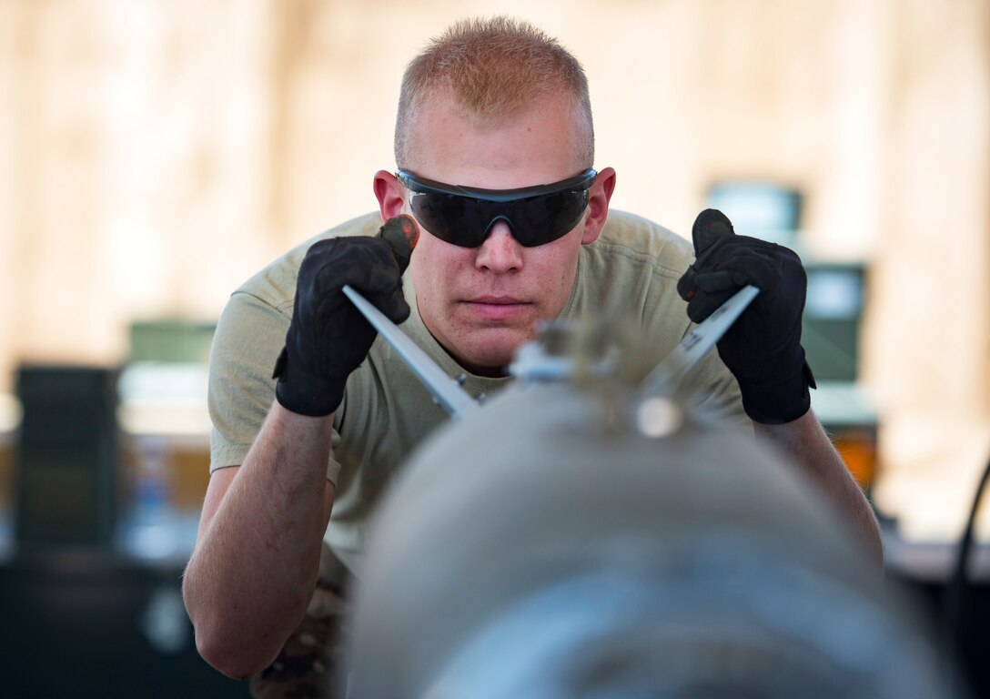 An airman aligns a guided bomb.