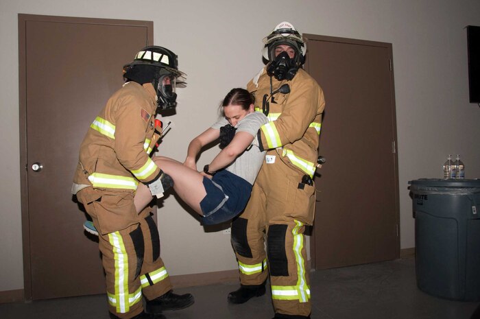 Two firefighters perform a two-man carry while extracting a simulated victim from a building during a fire response exercise Friday, 11 August 2017, at an undisclosed location in Southwest Asia. (U.S. Air Force photo by Master Sgt. Eric M. Sharman)