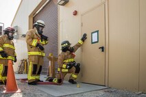 Senior Airman Hunter Blackmon (right), a firefighter with the 386th Expeditionary Civil Engineer squadron here checks the heat resonating from an entry door during a training scenario Friday, August 11, 2017, at the PERSCO building at an undisclosed location in Southwest Asia. (U.S. Air Force photo by 1st Lt. Rashard Coaxum)