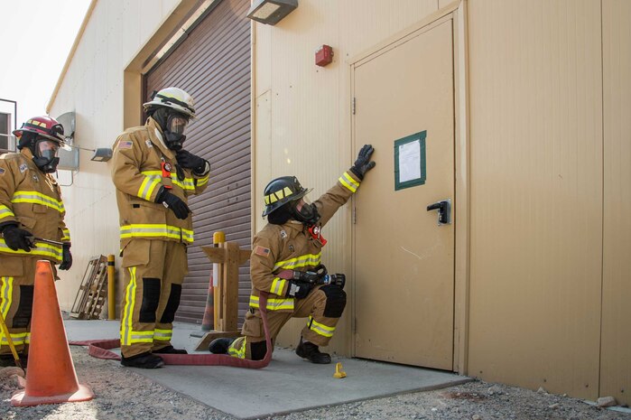 Senior Airman Hunter Blackmon (right), a firefighter with the 386th Expeditionary Civil Engineer squadron here checks the heat resonating from an entry door during a training scenario Friday, August 11, 2017, at the PERSCO building at an undisclosed location in Southwest Asia. (U.S. Air Force photo by 1st Lt. Rashard Coaxum)