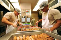 U.S. Air Force Tech. Sgts. Joshua Leon Guerrero, left, and Nicolas Garrido, both services craftsmen assigned to the 254th Force Support Squadron, Guam Air National Guard, prepare a lunch entree at the Two Seasons dining facility, Aug. 9, 2017, during RED FLAG-Alaska (RF-A) 17-3, at Eielson Air Force Base, Alaska. The 254 FSS team was tasked to augment the 354 FSS during RF-A 17-3. (U.S. Air Force photo by Staff Sgt. Jerilyn Quintanilla)