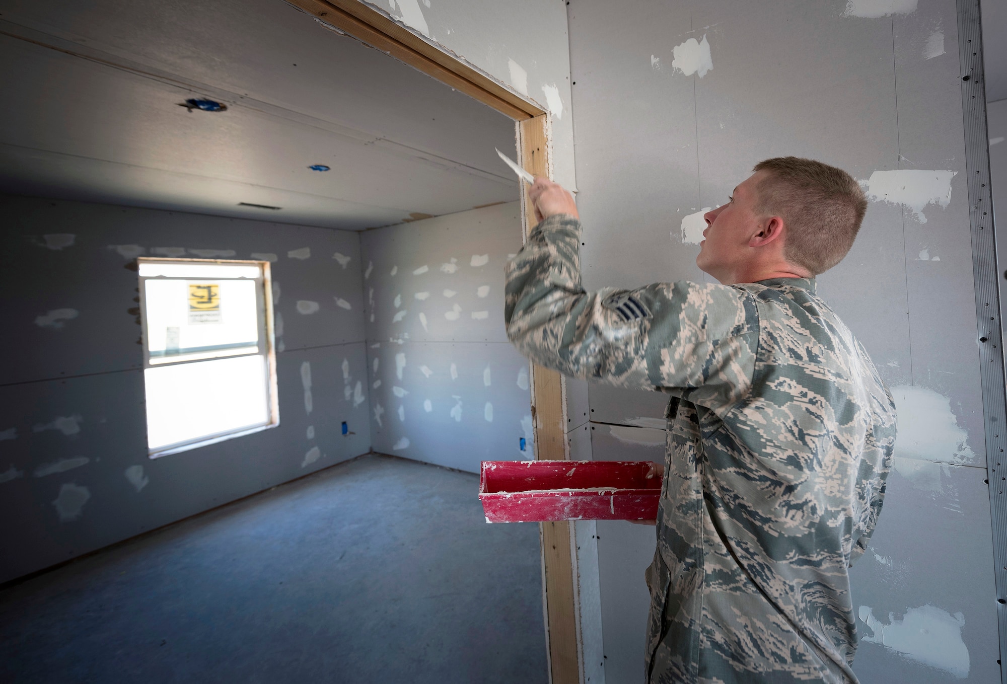 U.S. Air Force Senior Airman Drew Foes, an electrical power production specialist with the 182nd Civil Engineer Squadron, Illinois Air National Guard, applies drywall compound over screw heads in Crow Agency, Mont., July 27, 2017. The squadron helped build homes for Crow Nation veterans as part of the Department of Defense’s Innovative Readiness Training civil-military relations program. (U.S. Air National Guard photo by Tech. Sgt. Lealan Buehrer)