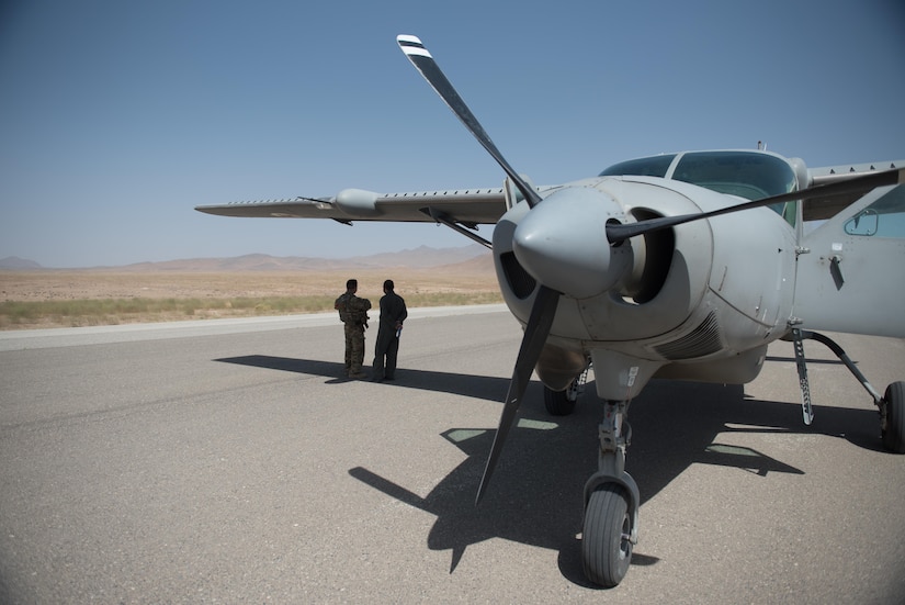 Airmen stand outside plane on flight line