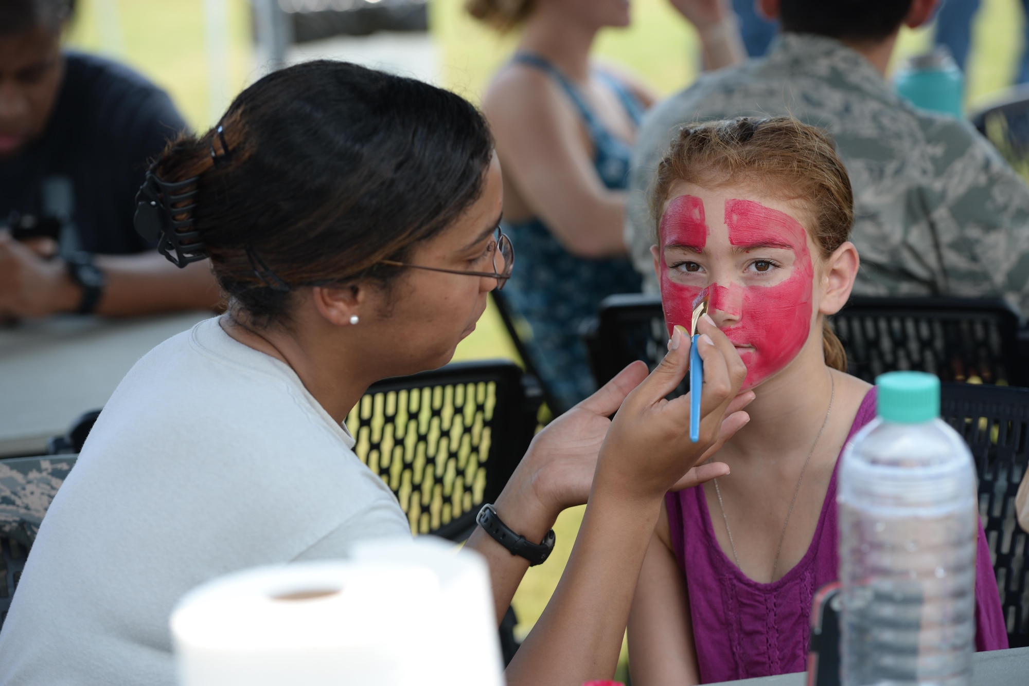 Senior Airman Nabila Ivaldi, the 14th Flying Training Wing Command Chief Executive Assistant, paints a superhero mask on Madison Shaw, daughter of John Ortiz, former staff sergeant from the 14th Security Forces Squadron, Aug. 4, 2017, on Columbus Air Force Base, Mississippi. Face painting, multiple inflatable water slides and a dunk tank were available at the End of Summer Bash, a family friendly event on Columbus AFB. (U.S. Air Force photo by Airman 1st Class Keith Holcomb)