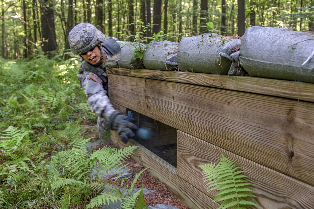 A soldier throws a grenade into a wooden structure.