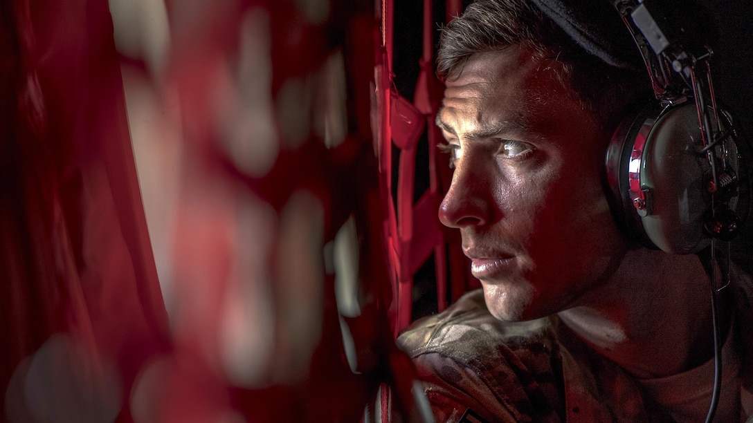 An airman looks out of a helicopter window.