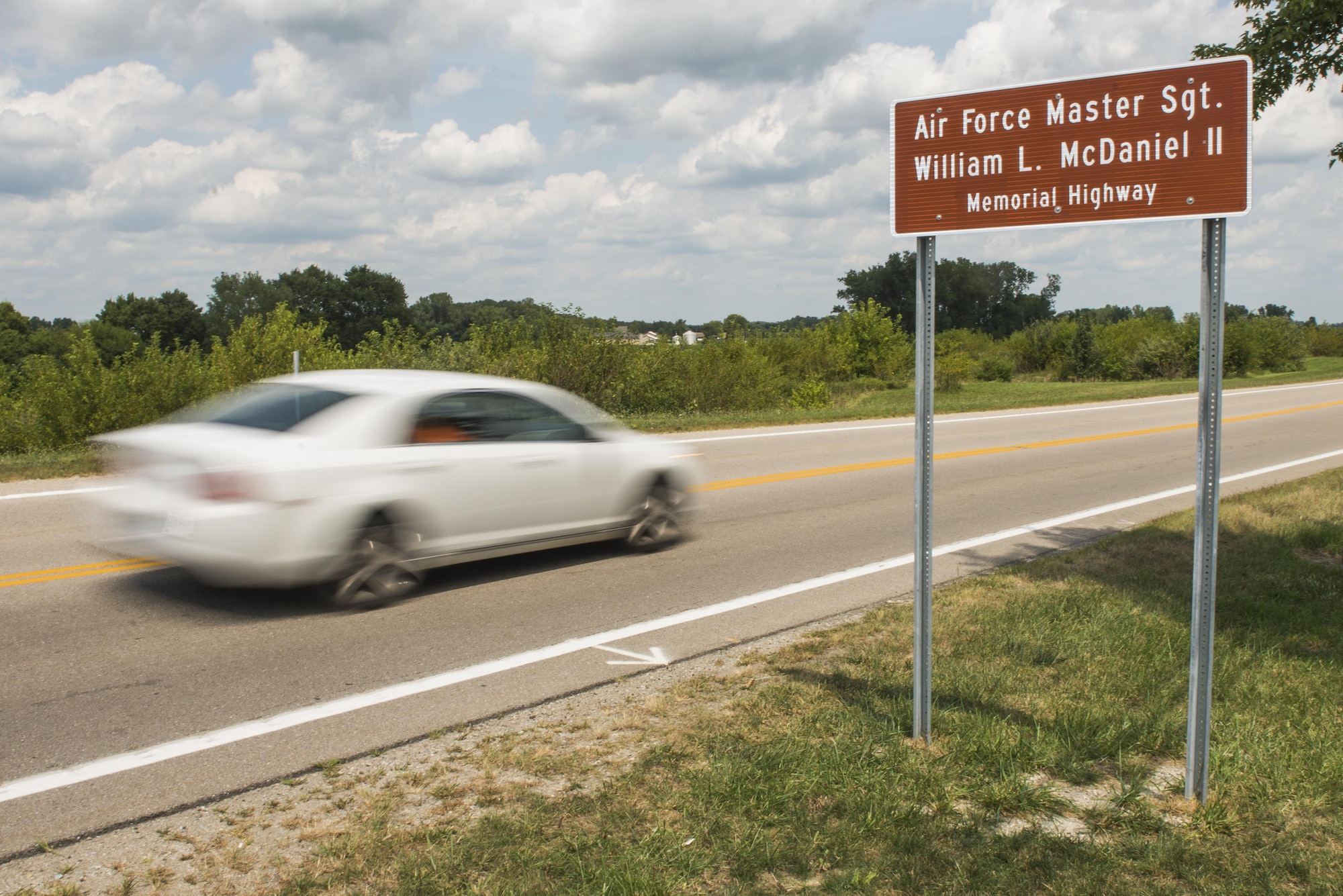 A car drives by the newly unveiled highway sign following a ceremony dedicating a six-mile stretch of Highway 121 in honor of Master Sgt. William L. McDaniel II's namesake in Greenville, Ohio, Aug. 14, 2017. McDaniel was a a Special Tactics pararescueman who was killed when the MH-47 Chinook helicopter he was in crashed in the Philippines Feb. 22, 2002. A pararescueman’s unique technical rescue skill sets are utilized during humanitarian and combat operations; they deploy anywhere, anytime, employ air-land-sea tactics into restricted environments to authenticate, extract, treat, stabilize and evacuate injured or isolated personnel. (U.S. Air Force photo by Wesley Farnsworth)