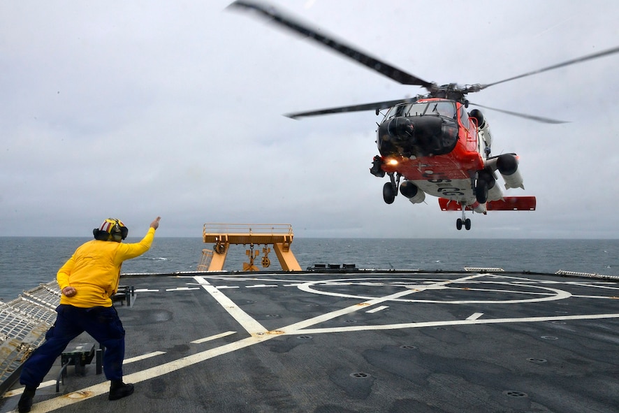 MST1 Sean Carrillo gives the “take-off” signal to the HH-60 during flight operations.