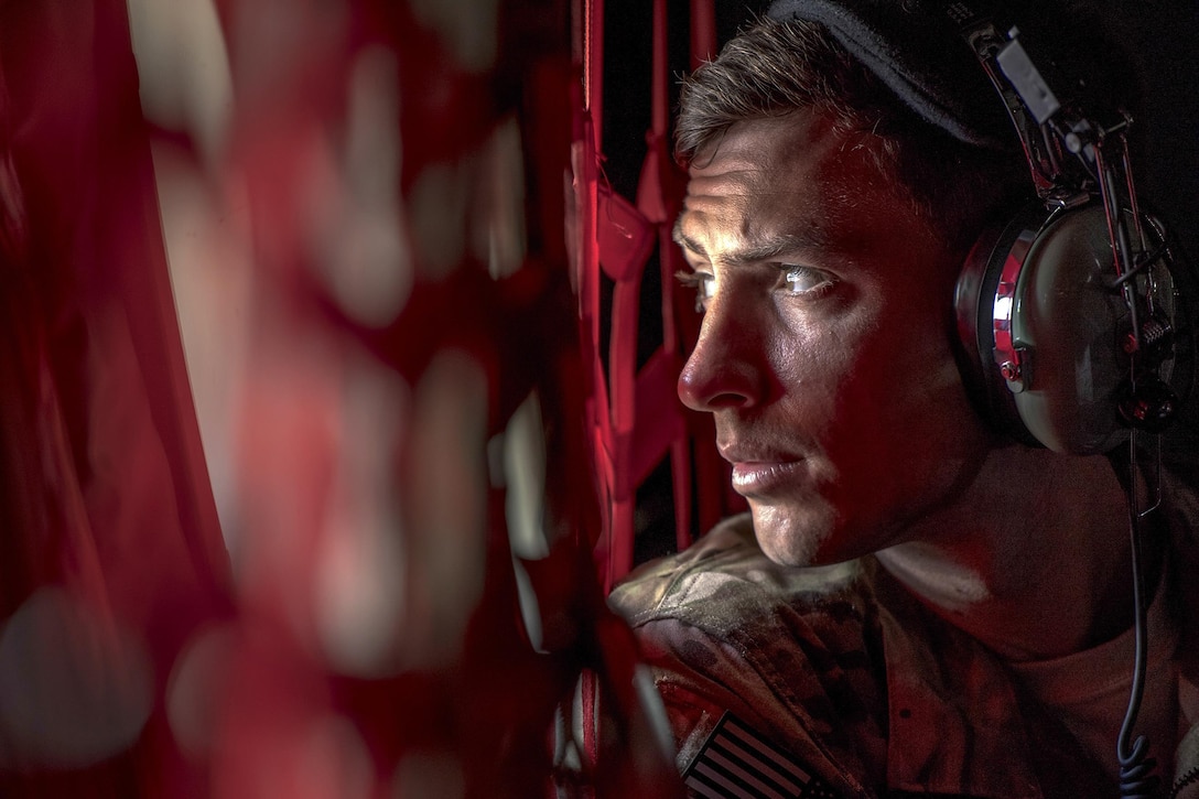 An airman looks out of a helicopter window.