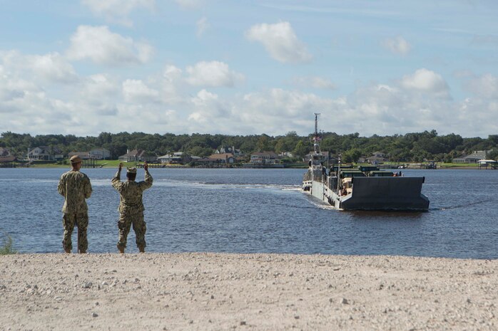 Sailors signal a landing craft to land on a beach to conduct lighterage during a maritime prepositioning force exercise at Blount Island, Fla., Aug. 13, 2017