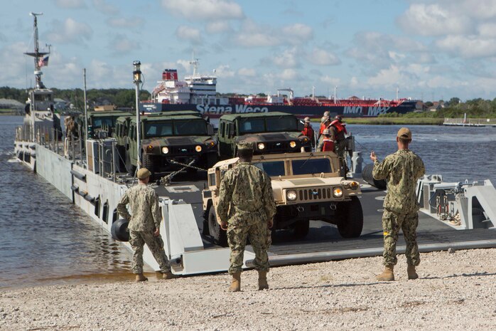 Sailors signal a landing craft to land on a beach to conduct lighterage during a maritime prepositioning force exercise at Blount Island, Fla., Aug. 13, 2017