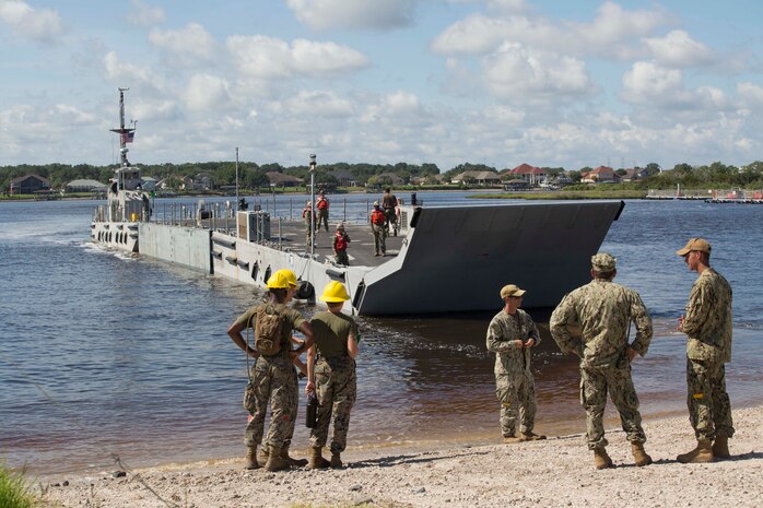 Sailors signal a landing craft to land on a beach to conduct lighterage during a maritime prepositioning force exercise at Blount Island, Fla., Aug. 13, 2017