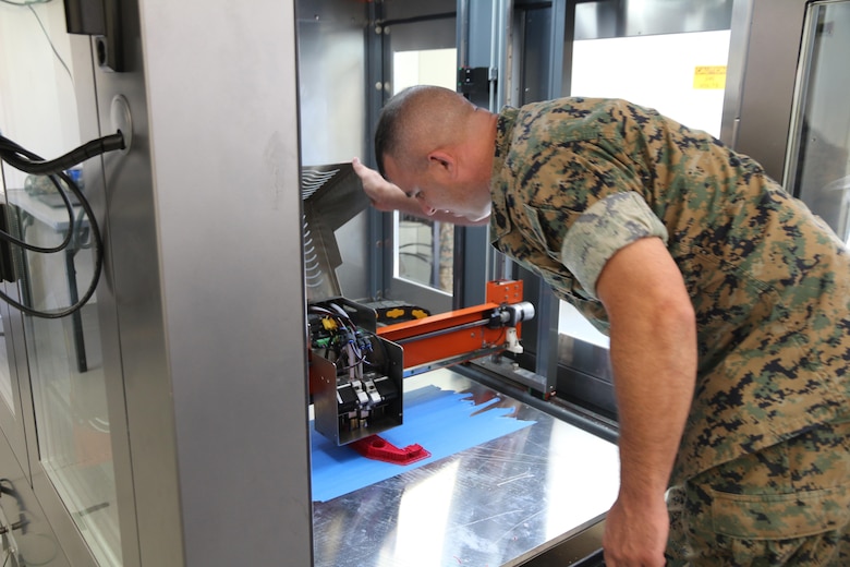 Gunnery Sgt. Doug McCue, a machinist with the 2nd Maintenance Battalion at Camp Lejeune, North Carolina, demonstrates the capabilities of a large-build 3-D printer in the X-FAB Facility Aug. 1. The X-FAB, or Expeditionary Fabrication, Facility is a self-contained, transportable additive manufacturing lab comprised of a 20-by-20-foot shelter, 3-D printers, a scanner and computer-aided design software system that can be used to fabricate repair and replacement parts in the field. The Marine Corps is exploring this expeditionary capability to expedite heavy equipment repairs in deployed environments. (U.S. Marine Corps photo by Kaitlin Kelly)