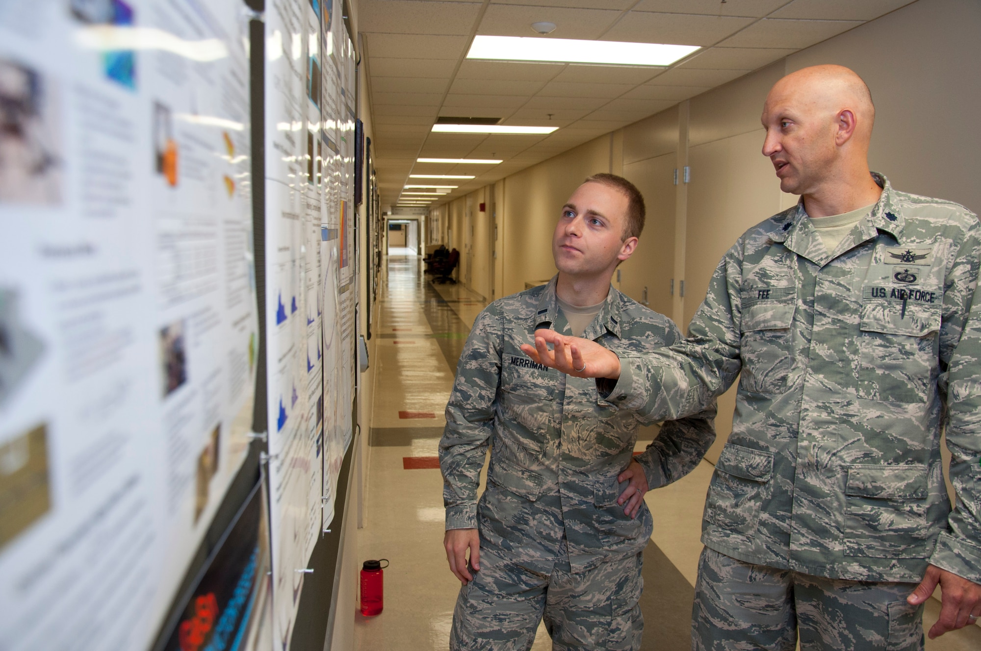 WRIGHT-PATTERSON AIR FORCE BASE, Ohio – Lt. Col. James Fee, Air Force Institute of Technology assistant professor of nuclear engineering, discusses electromagnetic pulse and how to model it from a nuclear weapon with 1st. Lt. Cameron Merriman, an AFIT student, June 22 using a display board hung in one of AFIT’s corridors. (U.S. Air Force photo/John Harrington)
