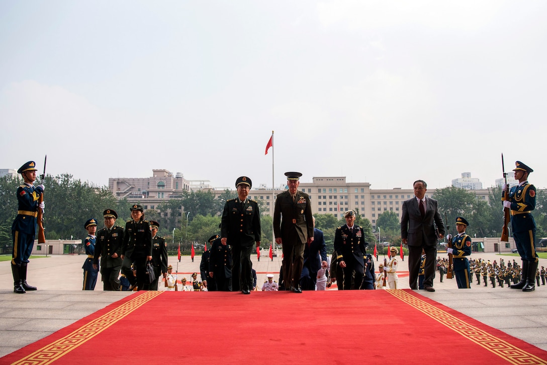 Military leaders walk on a red carpet in Beijing.