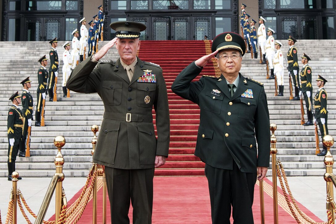 Marine Corps Gen. Joe Dunford stands next to Chinese Army Gen. Fang Fenghui, both men are saluting.