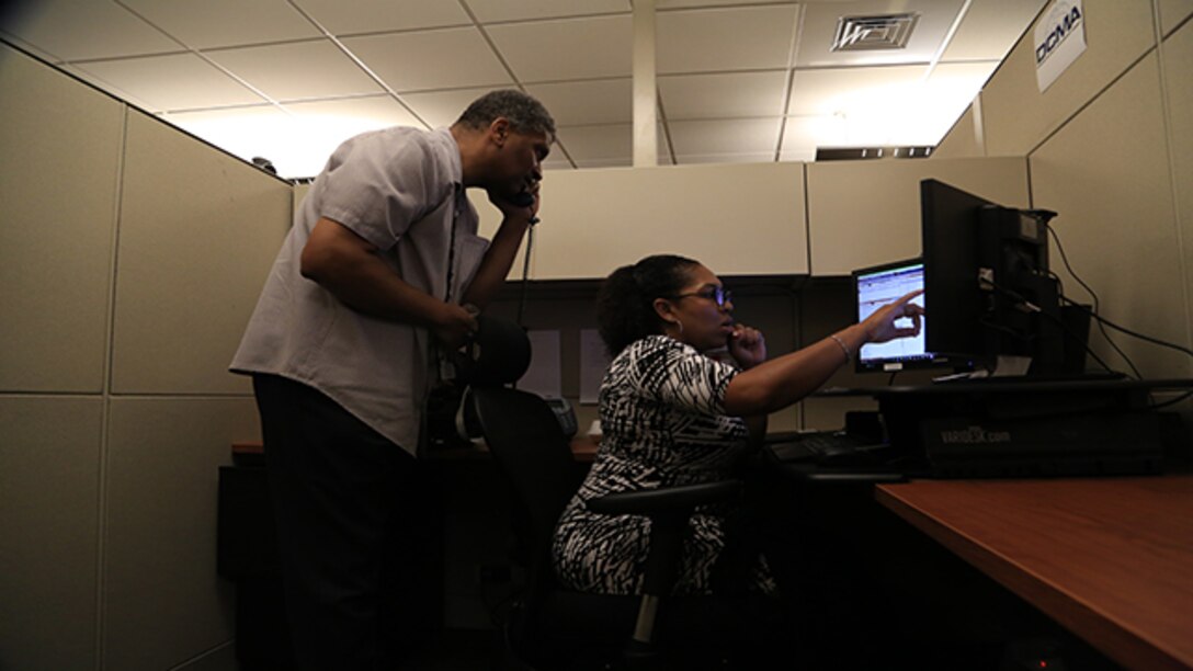 Defense Contract Management Agency video teleconferencing professionals, Terence Arrington and April Schulter, manage multipoint conferences during the global all hands from Fort Lee, Virginia, July 26, 2017. (DCMA photo by Elizabeth Szoke)