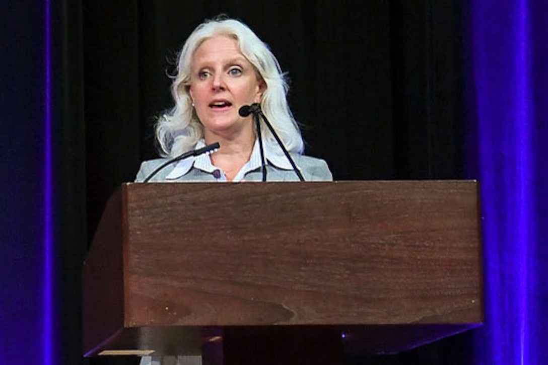 A woman stands behind a podium to make a speech.