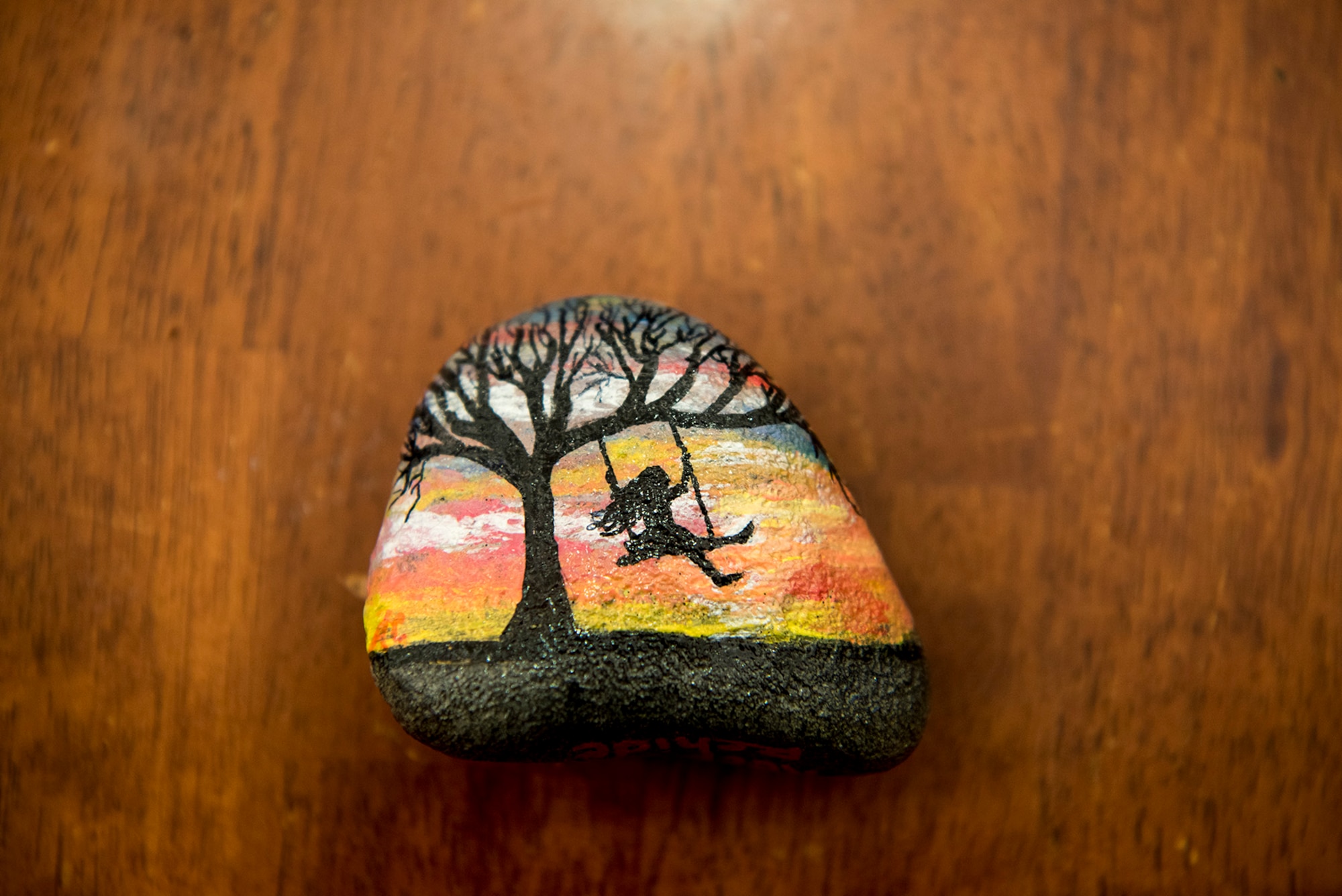Members of PAFB rocks! paint rocks to display and hide around Peterson Air Force Base, Colo., for others to find. Aug. 4, 2017. This rock was painted by Andrea Collis depicting a girl swinging on a tree during a sunset. (U.S. Air Force photo by Steve Kotecki)