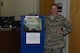 Staff Sgt. Megan Storms, 90th Force Support Squadron, reenlistments, extensions, enlisted promotions and retraining NCO in charge, poses near the new customer kiosk machine located at the Military Personnel Flight office at F.E. Warren Air Force Base, Wyo., August 9, 2017. The new system was installed to alleviate long wait times. (U.S. Air Force photo by Terry Higgins)