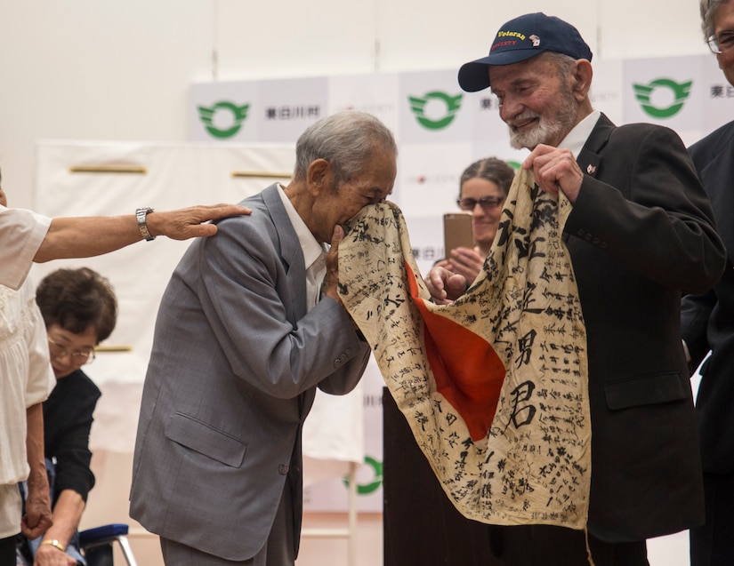 Tatsuya Yasue, left, receives a flag from World War II veteran Marvin Strombo at Higashishirakawa Village, Gifu Prefecture, Japan, Aug. 15, 2017.