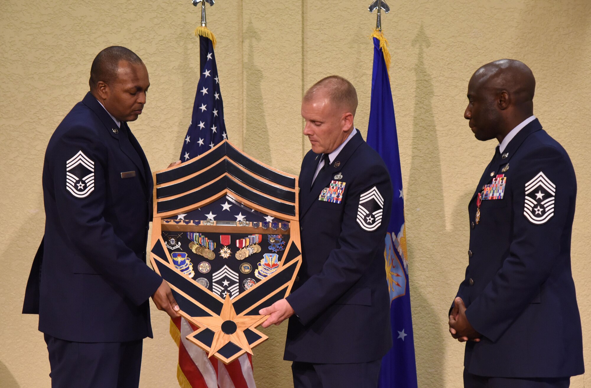 Chief Master Sgts. James Yarber, 89th Airlift Support Group superintendent, and Christopher Walker, 78th Mission Support Group superintendent, present Chief Master Sgt. Vegas Clark, former 81st Training Wing command chief, with a shadow box during his retirement ceremony in the Bay Breeze Event Center Aug. 11, 2017, on Keesler Air Force Base, Miss. Clark retired with 22 years of military service. Prior to his assignment at Keesler he served as the command chief for the 39th Air Base Wing, Incirlik Air Base, Turkey. (U.S. Air Force photo by Kemberly Groue)