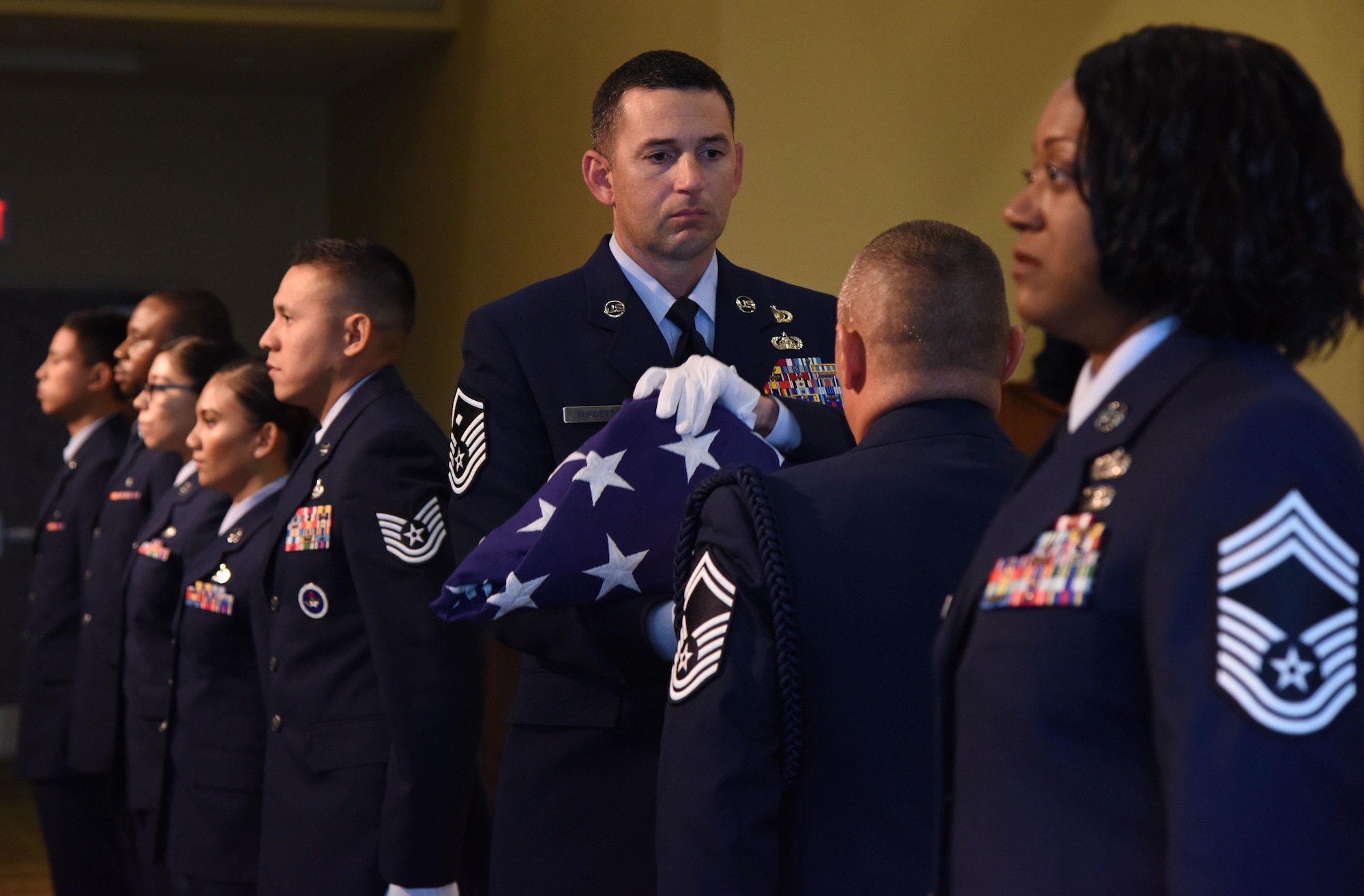 Master Sgt. Jason Burdett, 81st Security Forces squadron first sergeant, participates in a passing of the flag ceremony during a retirement ceremony for Chief Master Sgt. Vegas Clark, former 81st Training Wing command chief, in the Bay Breeze Event Center Aug. 11, 2017, on Keesler Air Force Base, Miss. Clark retired with 22 years of military service. Prior to his assignment at Keesler he served as the command chief for the 39th Air Base Wing, Incirlik Air Base, Turkey. (U.S. Air Force photo by Kemberly Groue)
