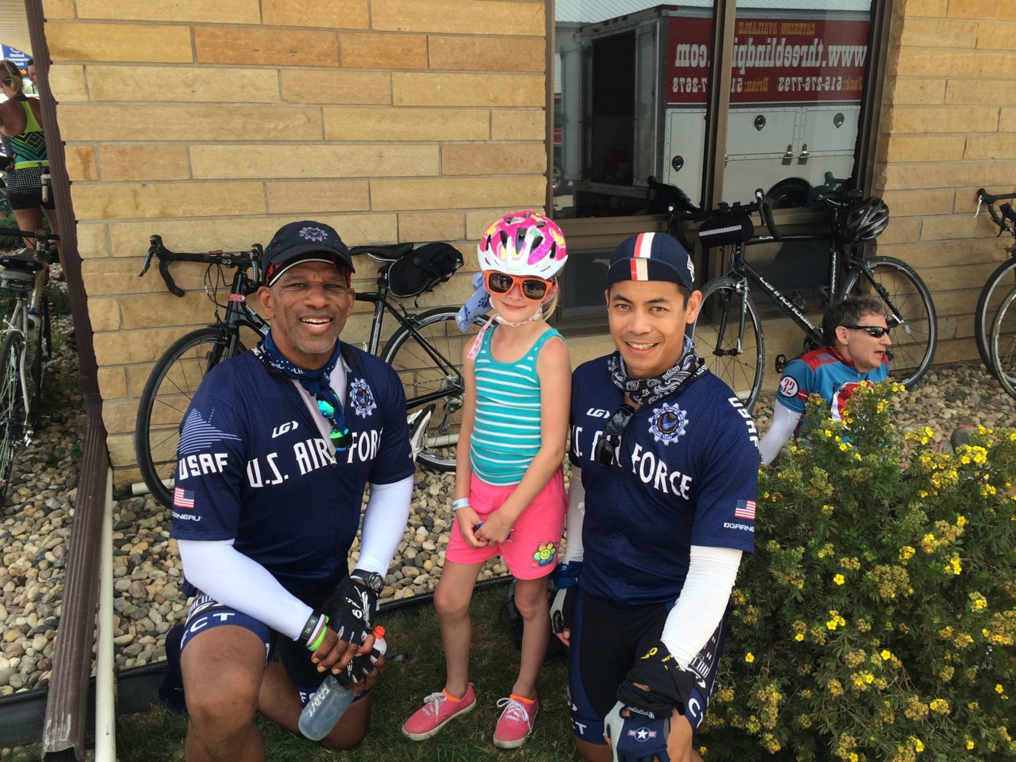Lt. Col. Tom Black and Lt. Col. Vince Zabala, both from the 618th Air Operations Center, stop to pose with a young cyclist during the RAGBRAI. Black and Zabala were part of nine Scott Air Force Base members who took part in the seven-day event.