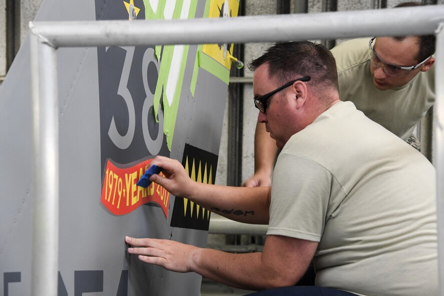 Tech. Sgt. Shawn Delaware, foreground, and Staff Sgt. Brandon Turner, both aircraft structural maintainers assigned to the 388th Maintenance Squadron, apply a decal on the tail of on an F-16 Fighting Falcon at Hill Air Force Base, Utah, Aug. 10, 2017. The aircraft pictured, the final operational Hill AFB F-16 to depart the base, will be featured in a ‘Viper Out’ ceremony scheduled for Sept. 8. (U.S. Air Force photo by R. Nial Bradshaw)