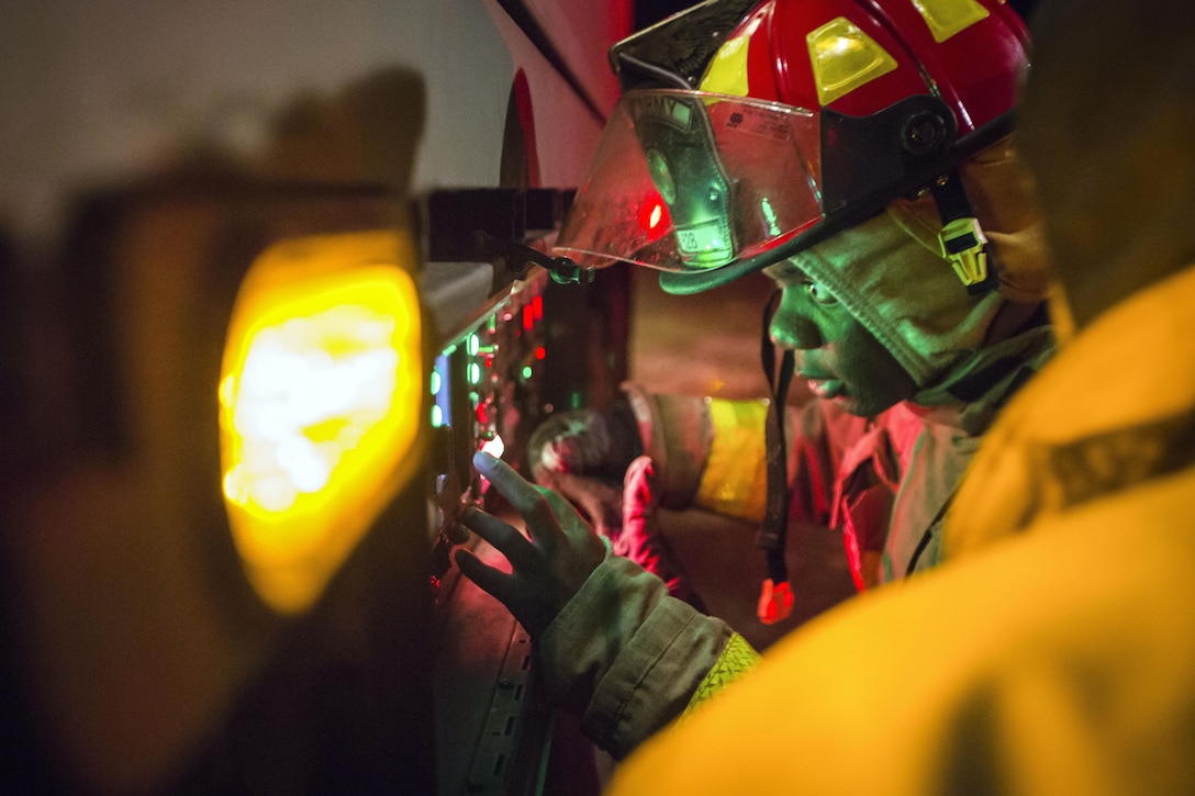 A firefighter is illuminated as he operates a control panel.