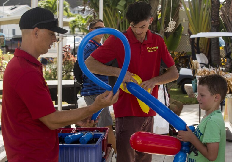 Employees with Adventure Balloons make a variety of balloon creations for children during the Klipper Summer Bash at Tiki Island aboard Marine Corps Base Hawaii, July 28, 2017. The Summer Bash is an annual event hosted by the Klipper Golf Course to strengthen a sense of community amongst residents of MCB Hawaii. (U.S. Marine Corps photo by Lance Cpl. Isabelo Tabanguil)