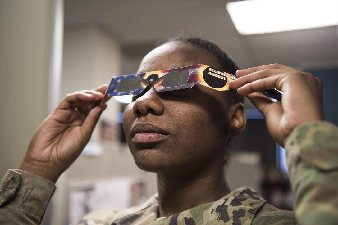 A service member puts on her eclipse safety glasses.
