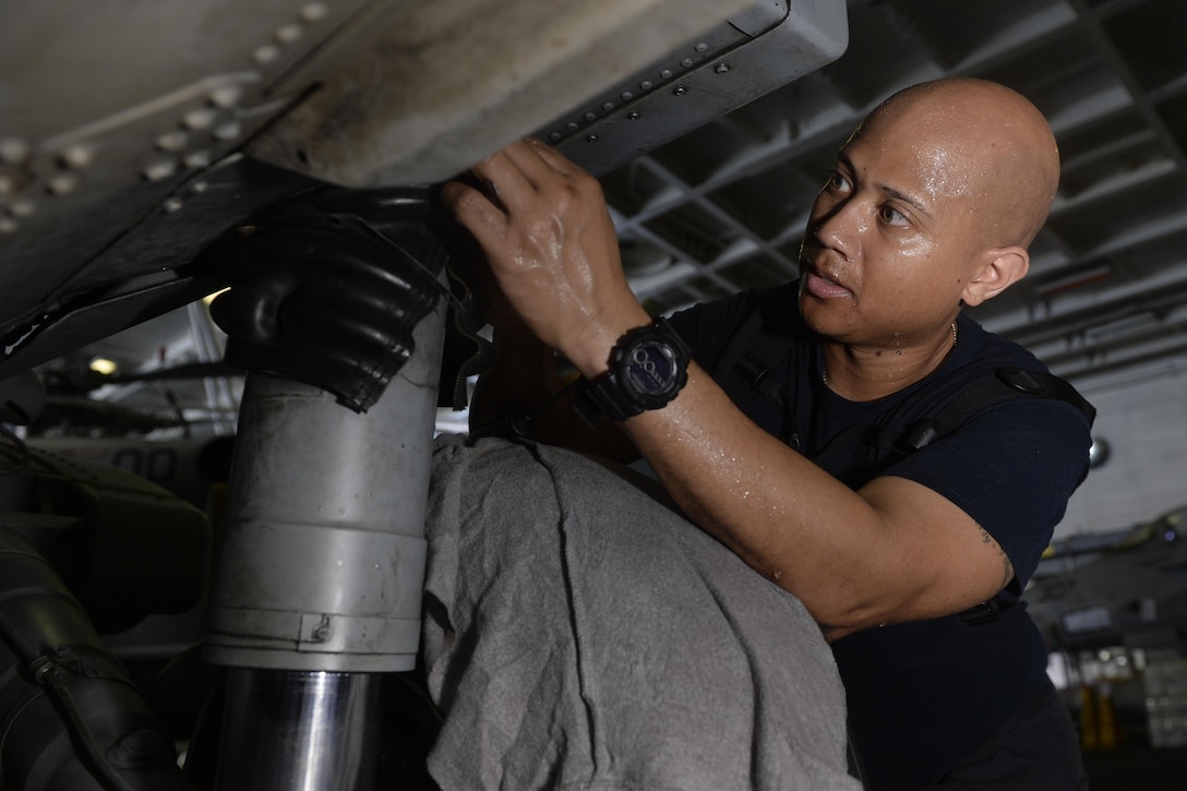 Navy Seaman Clifton Hill performs maintenance.