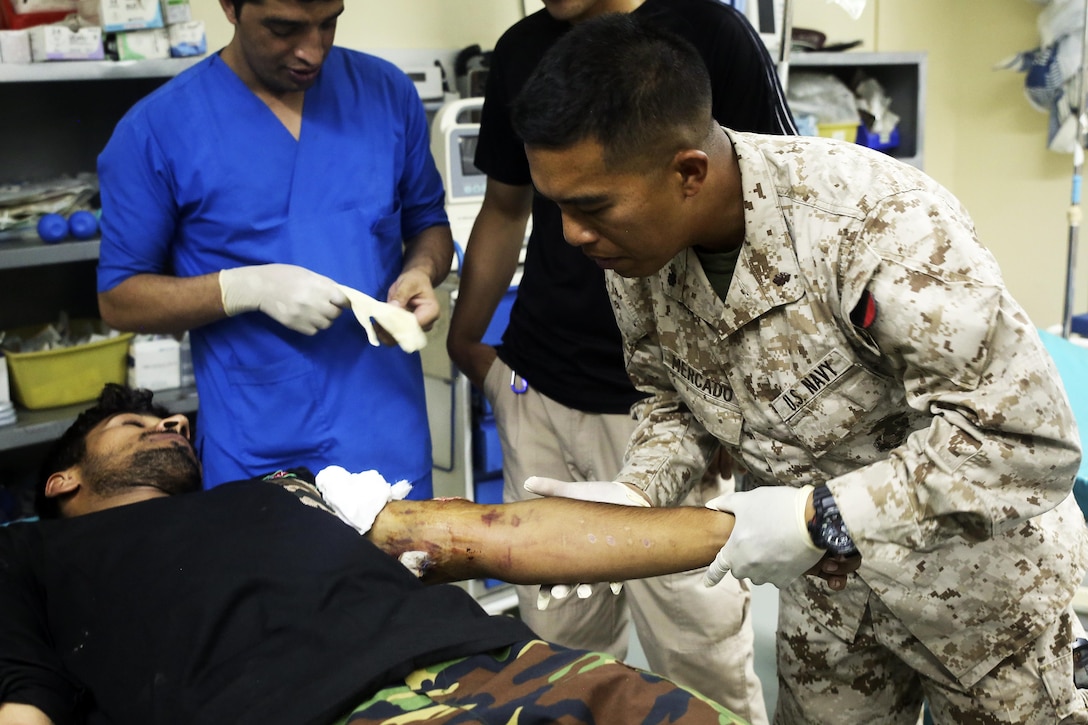 A surgeon and medical advisor, examines a gunshot wound on an Afghan National Army soldier.